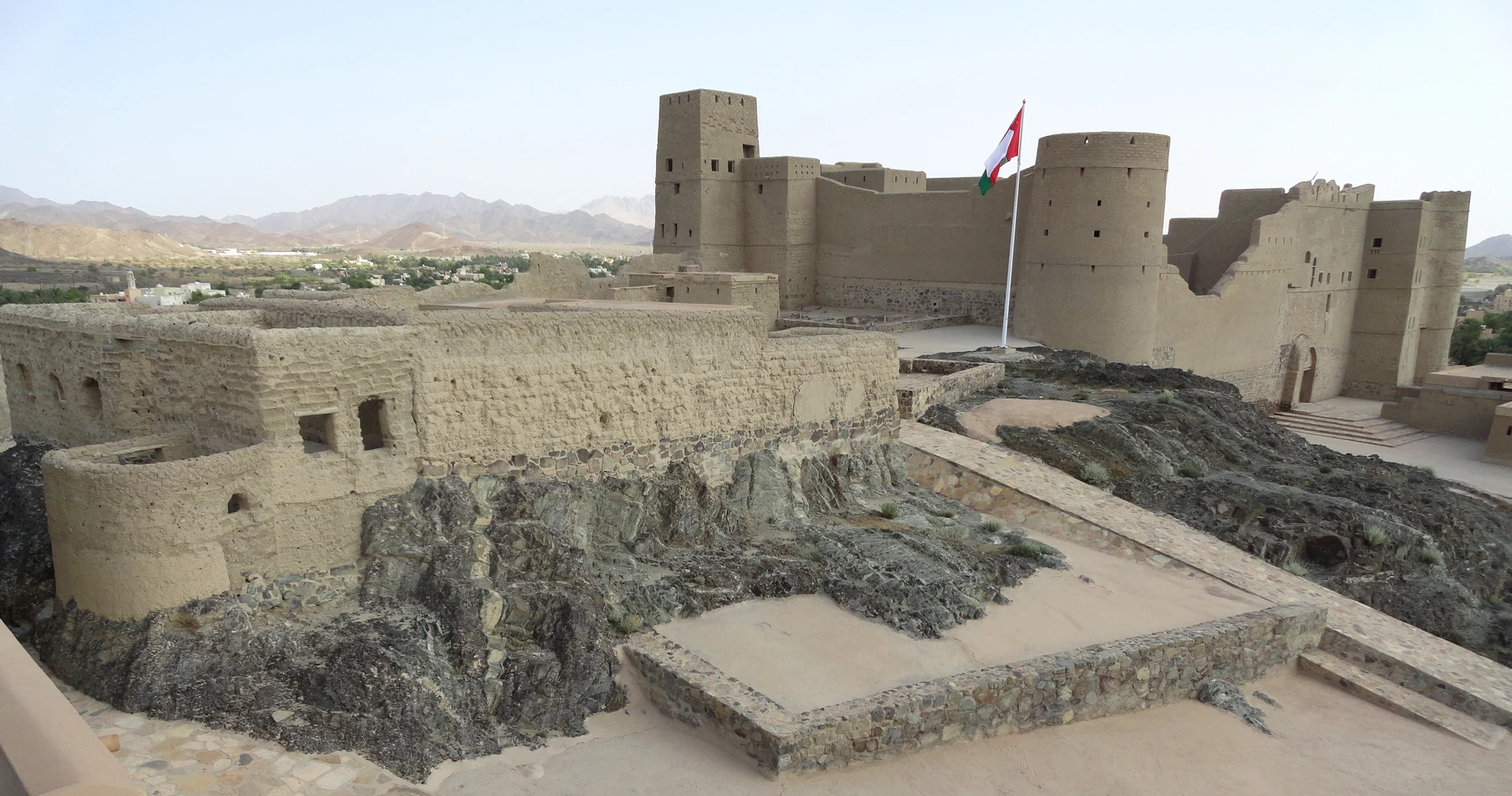 قلعة بهلا بأسوارها وأبراجها مع بساتين النخيل خلفها